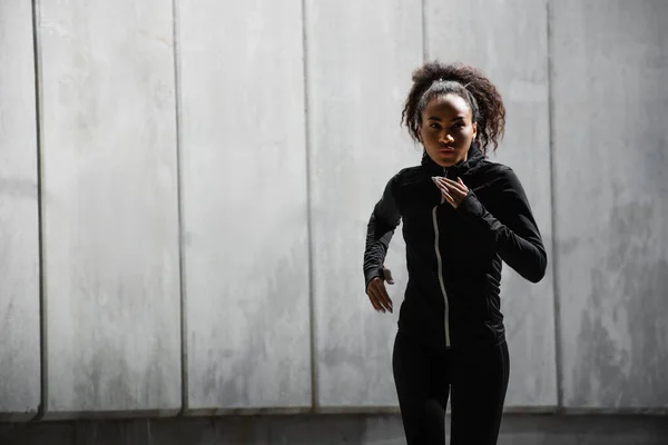 African american woman running near building