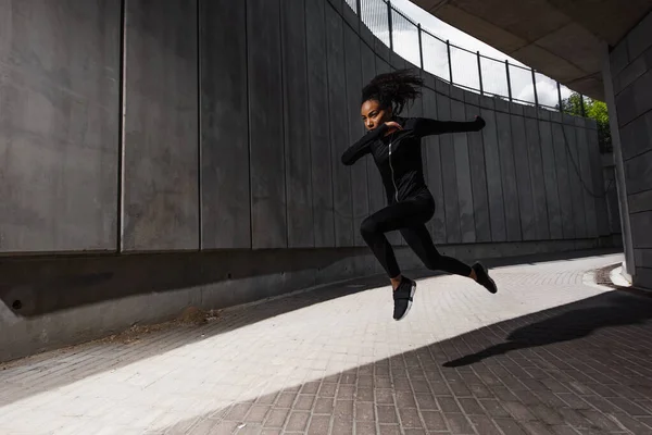 スポーツウェアを着たアフリカ系アメリカ人女性が街を飛び回る — ストック写真