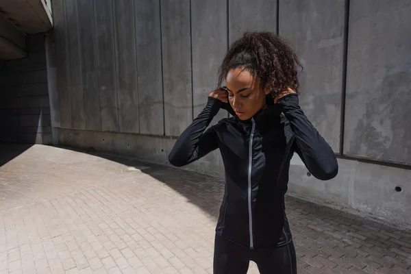 African American Sportswoman Adjusting Hood Sports Jacket Outdoors — Stock Photo, Image