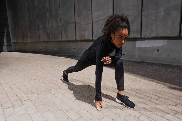 African american runner standing in starting pose on urban street 