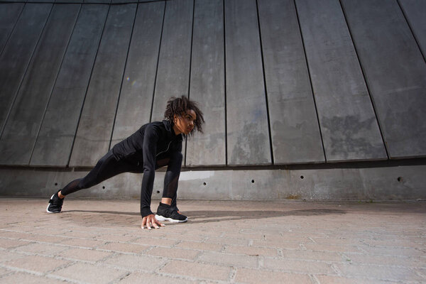Low angle view of african american woman standing in starting pose before run 