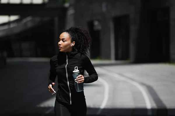 Africano Corredor Americano Fone Ouvido Sem Fio Segurando Esportes Garrafa — Fotografia de Stock