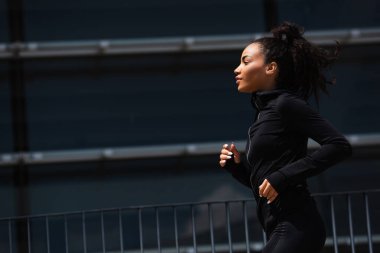 Kentsel caddede spor ceketli Afro-Amerikan koşucunun yan görüntüsü 