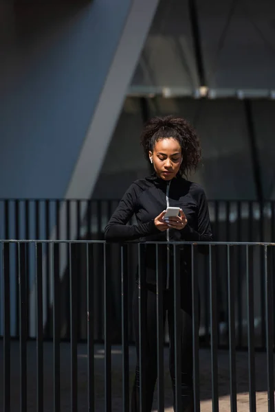 아프리카 미국인 야외에서 스마트폰을 사용하는 이어폰 — 스톡 사진