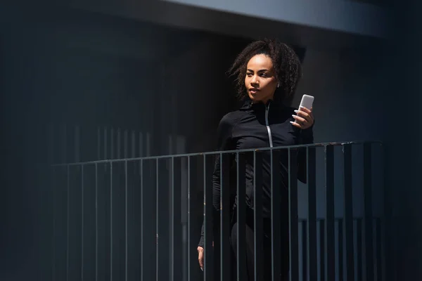 Pretty African American Sportswoman Earphone Holding Smartphone Outdoors — Stock Photo, Image