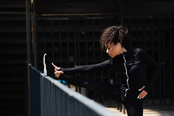 Zijaanzicht Van Afro Amerikaanse Sportvrouw Draadloze Oortelefoon Die Zich Uitstrekt — Stockfoto