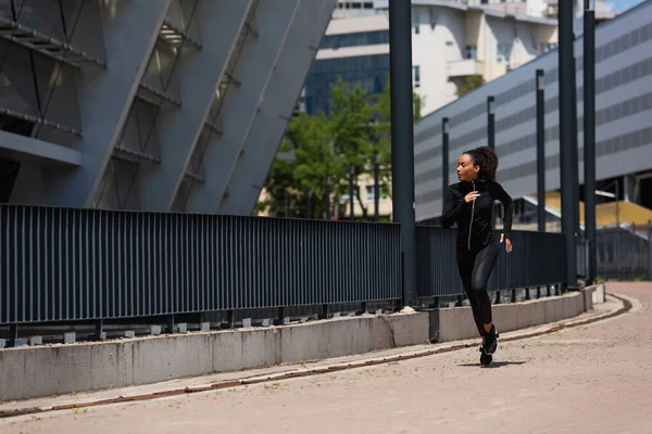 非洲裔美国女运动员在城市街道建筑物附近跑步的侧视图 — 图库照片