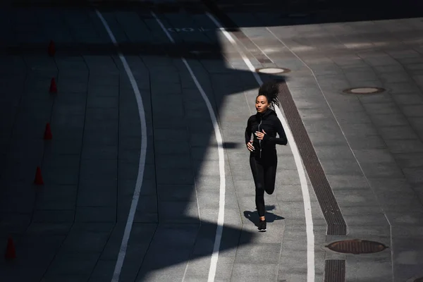 年轻的非洲裔美国女运动员在城市街道上跑步的高角图 — 图库照片