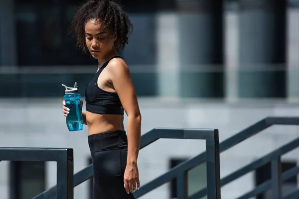 Joven Deportista Afroamericana Parte Superior Celebración Botella Deportiva Cerca Barandilla — Foto de Stock