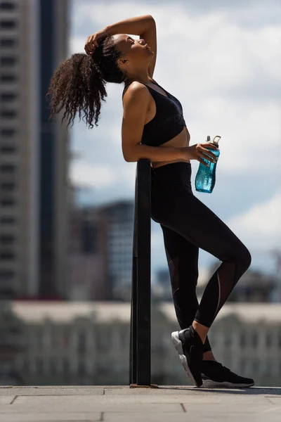 Side View African American Sportswoman Touching Hair Holding Bottle Outdoors — Stock Photo, Image