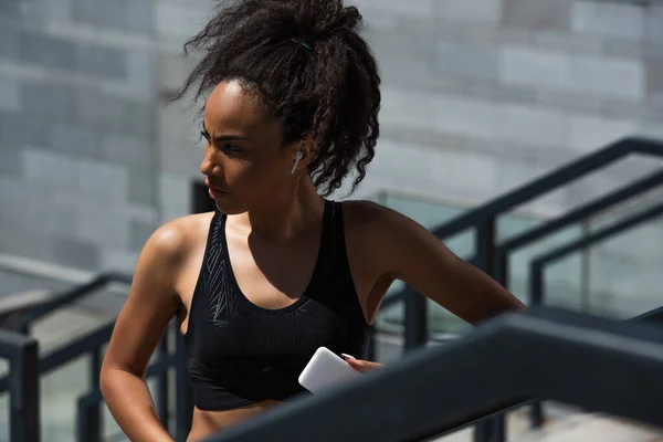 African American Sportswoman Earphone Holding Mobile Phone Outdoors — Stock Photo, Image