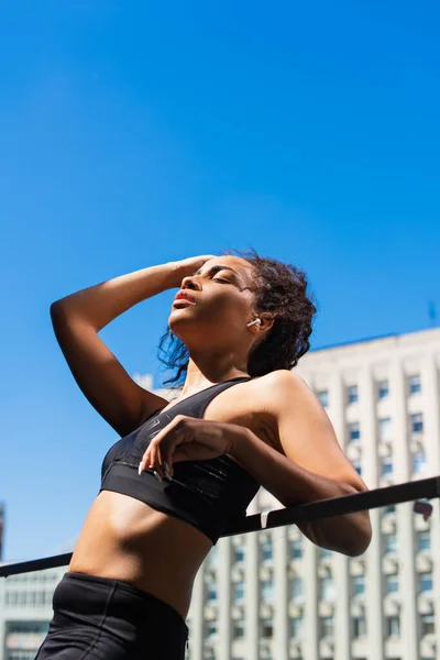 フィットアフリカ系アメリカ人スポーツ女性でイヤフォン休息で都市の通りに空と背景 — ストック写真