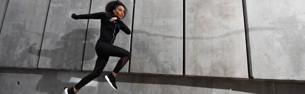 Африканская американская спортсменка бегает рядом со зданием на открытом воздухе, баннер 