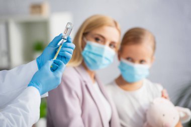 Çocuk doktoru tıbbi maskeli anne ve çocuğun yanında aşı buldu. 