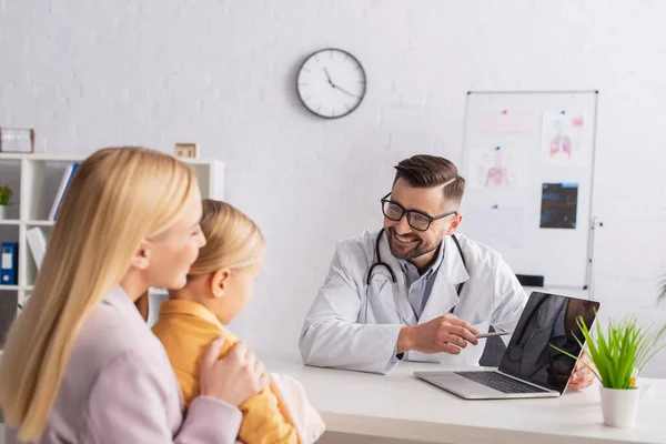 Positive Family Doctor Pointing Laptop Blank Screen Mother Kid Hospital — Stock Photo, Image