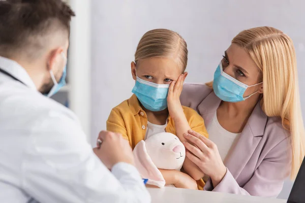 Niño Tocando Cabeza Cerca Madre Médico Borroso Bata Blanca —  Fotos de Stock