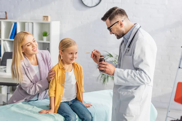 Leende Barnläkare Håller Sirap Nära Leende Patient Medicinsk Soffa — Stockfoto