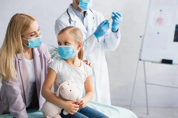 Madre Máscara Médica Mirando Hija Con Juguete Suave Cerca Del —  Fotos de Stock