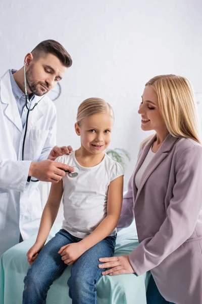 Sonriente Niño Mirando Cámara Cerca Mamá Médico Con Estetoscopio — Foto de Stock