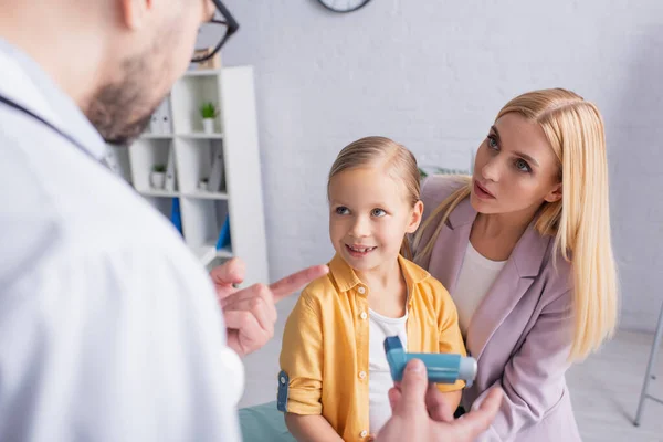 Frau Schaut Hausarzt Und Zeigt Auf Inhalator Neben Lächelnder Tochter — Stockfoto