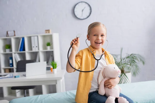 Szczęśliwa Dziewczyna Stetoskopem Miękką Zabawką Patrząc Kamerę Szpitalu — Zdjęcie stockowe