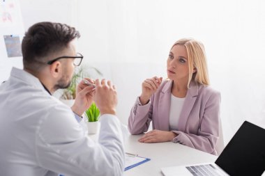 Sarışın kadın hastanede muayene sırasında doktoru dinliyor.