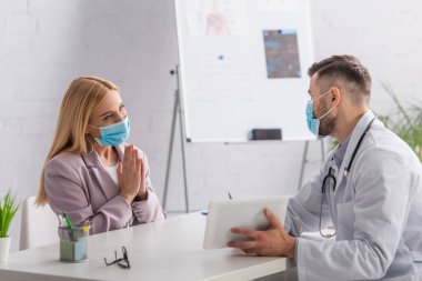 Koruyucu maskeli kadın lütfen dijital tabletli doktorun yanına yaklaşın.