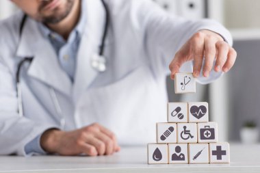 Bulanık doktorların piramitte tıbbi sembollerle küpleri sıralamasının kısmi görüntüsü