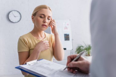 Kadın migrenden muzdarip. Bulanık doktor panoya yazı yazıyor.