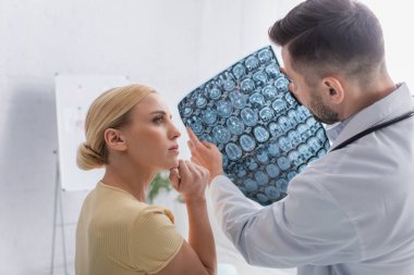 Doktor muayene sırasında MR taramasını kadınlara gösteriyor.