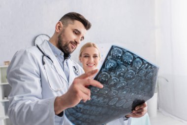 Doktorun ellerinde beyin taramasına bakan memnun bir kadın.
