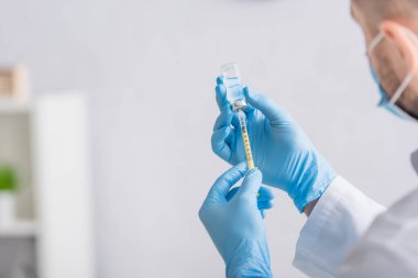 Doktorun lateks eldivenli hali şırıngayı aşıyla dolduruyor.
