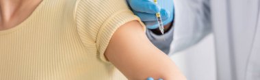 Doktorun aşılı kısmi görüntüsü klinikteki kadının yanında, pankartta