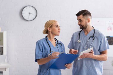 Klinikte konuşurken dijital tabletli doktorlar birbirlerine bakıyorlar.