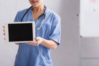 Mavi üniformalı doktorun elinde boş ekran ile dijital tablet tutarken çekilmiş görüntüsü