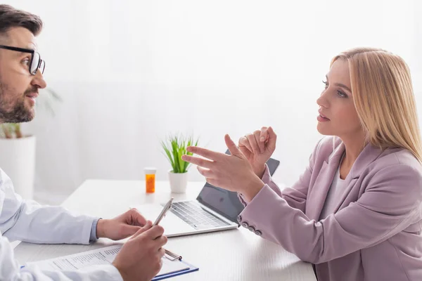 Mujer Rubia Haciendo Gesto Mientras Habla Con Médico Sala Consulta —  Fotos de Stock