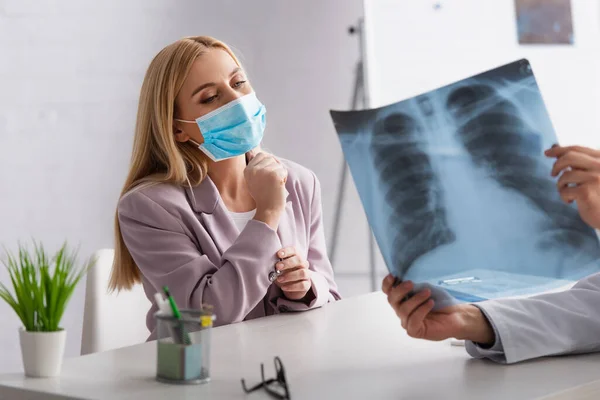 Беспокойная Женщина Медицинской Маске Смотрит Рентген Легких Руках Врача Клинике — стоковое фото