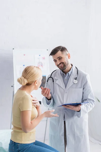 Sonriente Médico Con Portapapeles Hablando Con Mujer Rubia Clínica —  Fotos de Stock