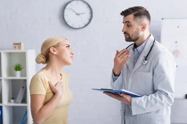 Mujer Enferma Tocando Pecho Cerca Del Médico Hablando Durante Consulta —  Fotos de Stock