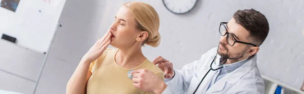 女性は咳をしながら医者は聴診器やバナーで調べます — ストック写真