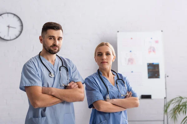 Médicos Uniforme Azul Mirando Cámara Mientras Están Pie Con Los — Foto de Stock