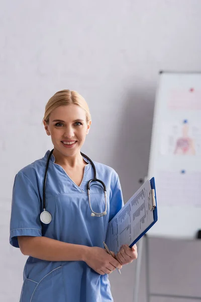 Médecin Blonde Tenant Presse Papiers Avec Diagnostic Tout Souriant Caméra — Photo