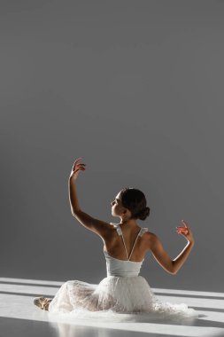 Beyaz elbiseli balerin ve gri arka planda dans eden sivri uçlu ayakkabının yan görüntüsü.