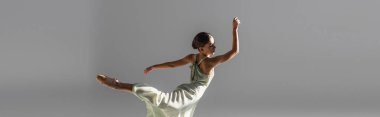 Sivri uçlu ayakkabı giyen genç balerin Gri pankartta tek başına dans ediyor 