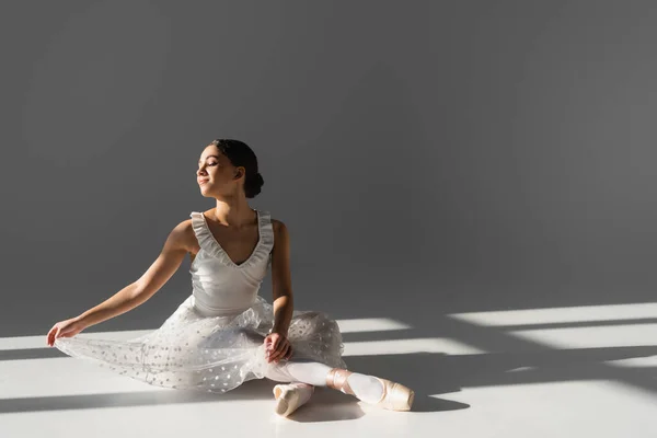Sivukuva Hymyilevä Tyylikäs Ballerina Istuu Harmaalla Taustalla — kuvapankkivalokuva