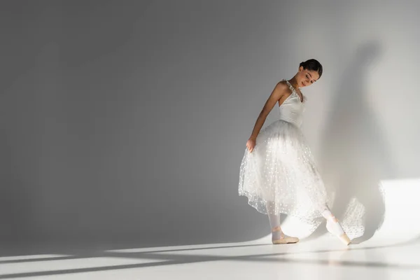Ballerina Betrachtet Spitzenschuh Auf Grauem Hintergrund — Stockfoto