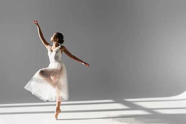 Boční Pohled Baletky Bílé Sukni Stojící Jedné Noze Šedém Pozadí — Stock fotografie