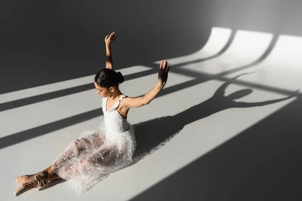 Side View Ballerina Raising Hands While Sitting Grey Background Sunlight — Stock Photo, Image