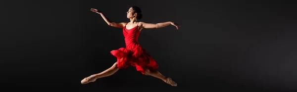 穿着尖皮鞋的芭蕾舞演员和穿着红色连衣裙跳在黑色横幅上的侧视图 — 图库照片