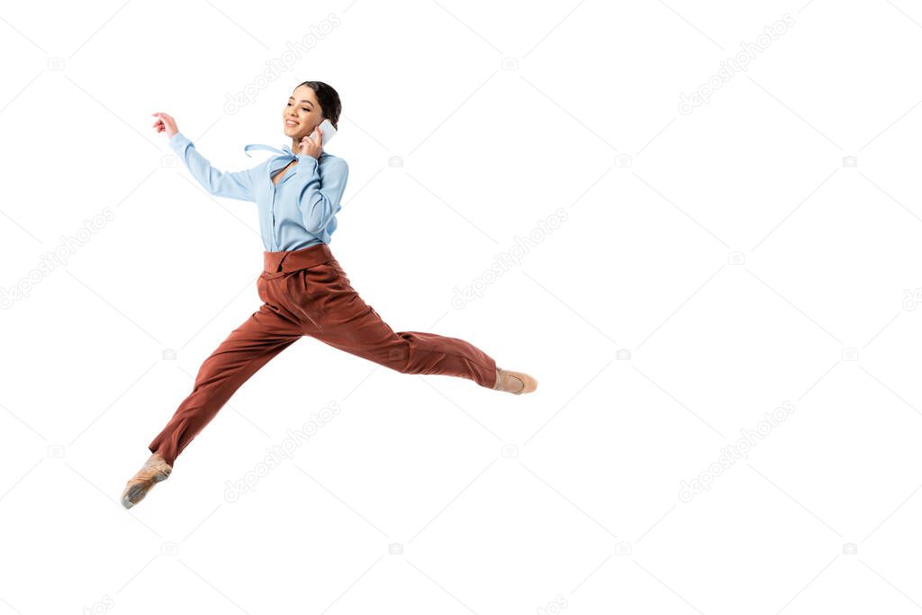 Smiling ballerina talking on smartphone while jumping isolated on white 
